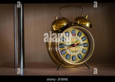 An old clock standing on a shelf of modern furniture. Stock Photo
