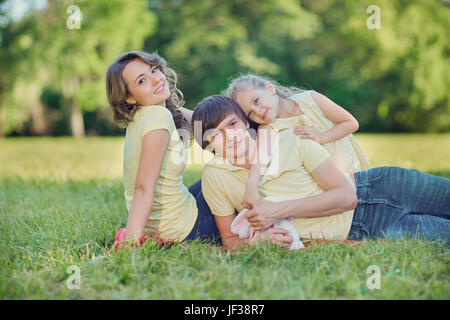 Happy family lying on grass in park. Stock Photo