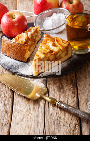 Delicious piece of apple pie with powdered sugar and juice close-up on the table. Vertical Stock Photo