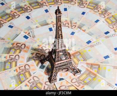 Eiffel Tower souvenir surrounded by vacation money. A lot of euro bills. Travel budget concept. Stock Photo