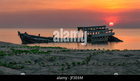 An old shipwreck or abandoned shipwreck panorama taken during a beautiful sunrise , Wrecked boat abandoned stand on beach or Shipwrecked off the coast Stock Photo