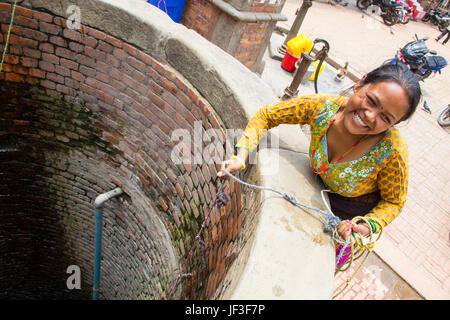 Young woman drawing water from a well in Bhaktapur, Kathmandu, Nepal Stock Photo