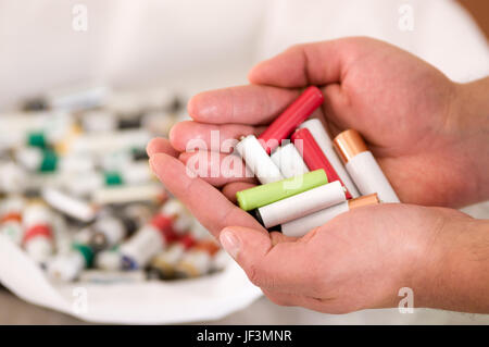 Close up of hand holding alkaline batteries heap, environment and ecology concept. Stock Photo