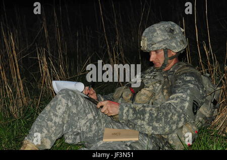 A 101st Airborne Division operator plots coordinates during night land navigation in the NCO and Soldier of the Year competition at Fort Campbell, Kentucky, demonstrating navigation and operational skills. Stock Photo
