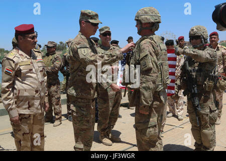 U.S. Army Maj. Timothy Batig, deployed in support of Combined Joint Task Force-Operation Inherent Resolve and assigned to 2nd Battalion, 508th Parachute Infantry Regiment, 2nd Brigade Combat Team, 82nd Airborne Division, receives his promotion to the rank of lieutenant colonel from Maj. Gen. Joseph Martin, the commanding general of Combined Joint Force Land Component Command and 1st Infantry Division, in Mosul, Iraq, May 25, 2017. The 2nd BCT, 82nd Abn. Div., enables the Iraqi security forces partners through the advise and assist mission, contributing planning, intelligence collection and ana Stock Photo