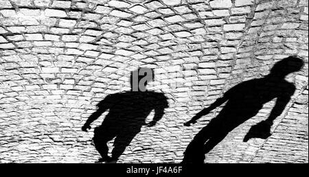 Shadows of two person on the old cobbled road in black and white; Stock Photo