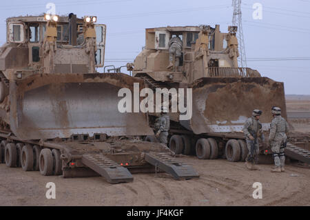 U.S. Army soldiers from Alpha Company, 3rd Special Troops Battalion, 3rd Brigade, 101st Airborne Division prepare to unload two armored Caterpillar D9 bulldozers from their carriers at Al Butoma, Iraq, on Jan. 11, 2006.  The soldiers will use the bulldozers to construct berms for security in Al Butoma.  DoD photo by Spc. Jose Ferrufino, U.S Army. Stock Photo