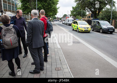 London, UK. 29th June, 2017. Attendees on a site visit by the London Assembly Transport Committee to the Walthamstow Mini Holland scheme in Waltham Forest stand by a blended 'Copenhagen' crossing, designed to slow down vehicles when entering or exiting side roads and to encourage drivers to give way to pedestrians crossing the road, as an emergency vehicle passes on Hoe Street. Credit: Mark Kerrison/Alamy Live News. Stock Photo