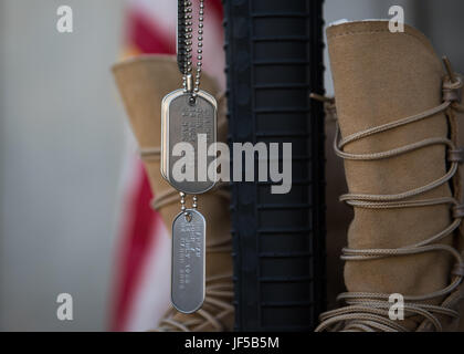 Dog tags, displaying the names of Airmen killed in action, hang off of a rifle during a Memorial Day ceremony at Bagram Airfield, Afghanistan, May 29, 2017. The boots, rifle and helmet make what is called the Battlefield Cross, which is a symbolic replacement of a cross and is used to honor and show respect to deceased service members. (U.S. Air Force photo by Staff Sgt. Benjamin Gonsier) Stock Photo