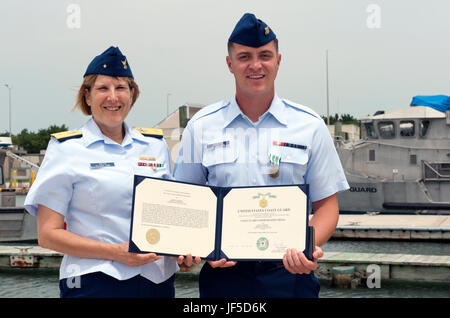 Coast Guard Rear Adm. Meredith Austin, commander, 5th Coast Guard District, poses with Fireman James Sanders after presenting him with the Coast Guard Commendation Medal at Coast Guard Sector Field Office Fort Macon in Atlantic Beach, North Carolina, May 31, 2017. Sanders rescued five women who fell into Taylor Creek after a pier collapsed at The Spouter Inn in Beaufort, North Carolina, May 11, 2016. (U.S. Coast Guard photo by Petty Officer 3rd Class Corinne Zilnicki/Released) Stock Photo