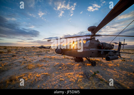 An AH-64 Apache Helicopter from 1st Battalion, 130th Aviation Regiment, North Carolina Army National Guard, sits under a sunset in the Mojave Desert May 30, 2017, at the National Training Center, Fort Irwin, California. (Mississippi National Guard photo illustration by Staff Sgt. Tim Morgan,102d Public Affairs Detachment) (This image was created using high dynamic range techniques) Stock Photo