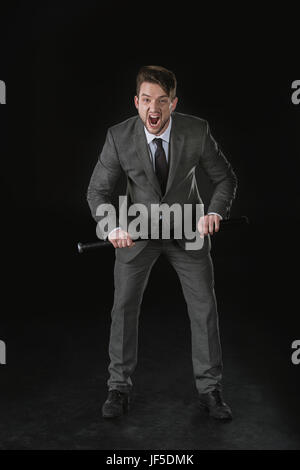 Angry businessman holding baseball bat and screaming isolated on black Stock Photo