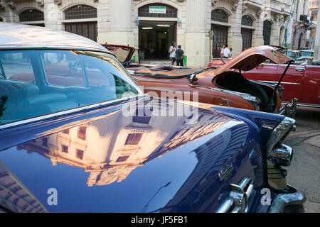 The Cuban architecture in downtown Havana is reflected off the trunk of a classic American car. Stock Photo