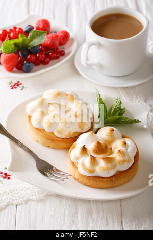 Lemon tart with meringue and coffee with milk close-up on the table. vertical Stock Photo