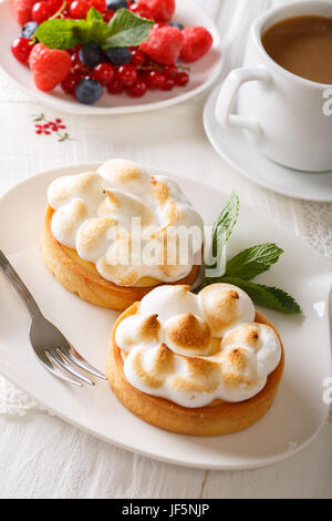 Tart with lemon curd, merengue and coffee with milk close-up on a plate. vertical Stock Photo