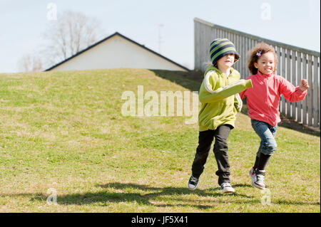 Two girls running down hill Stock Photo