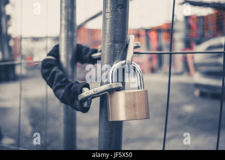 chain and padlock on gate at construction site - lock on closed fence Stock Photo