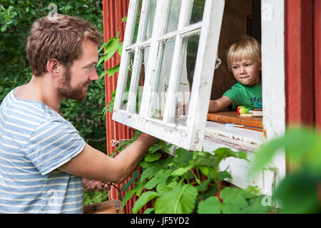 Father holding sons hand through window Stock Photo