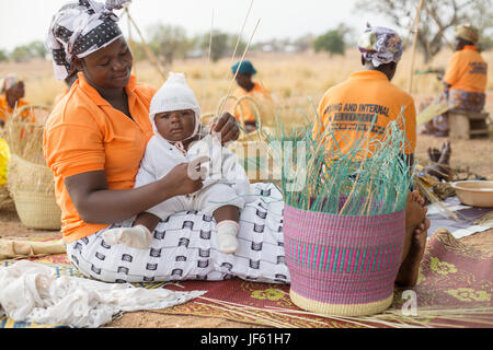 Women from a weaver’s cooperative weave traditional straw baskets together in Upper East Region, Ghana. Stock Photo