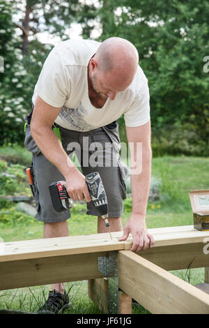 Mid-adult man drilling plank Stock Photo