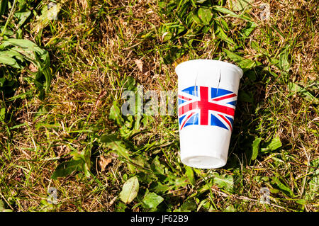 An empty plastic cup printed with the Union Jack lying on grass. Stock Photo