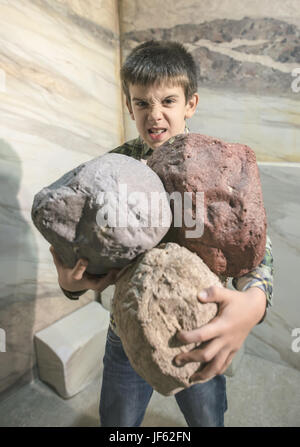 Strong child holds heavy stones Stock Photo