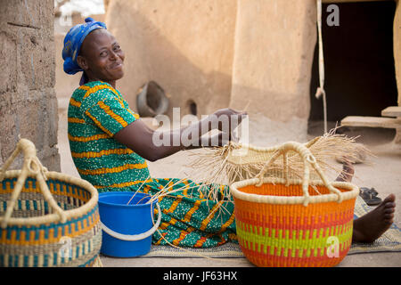 A woman weaves traditional straw baskets in Upper East Region, Ghana. Stock Photo