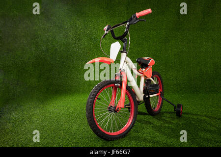 Kids bicycle parked on the green grass at outdoor park Stock Photo