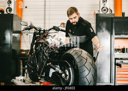 Mechanician changing motorcycle wheel in bike repair shop Stock Photo