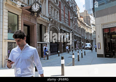 Businessman walking along Throgmorton Street at noon texting  on mobile phone in Square Mile financial district City of London EC2 UK    KATHY DEWITT Stock Photo