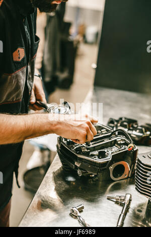 Cropped image of automobile mechanic repairing motorcycle in automobile store. Biker repairing his custom motorcycle Stock Photo