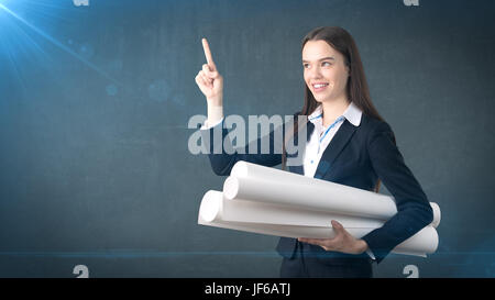 Building, developing, consrtuction and architecture concept - smiling beautiful businesswoman in suit with blueprint Stock Photo