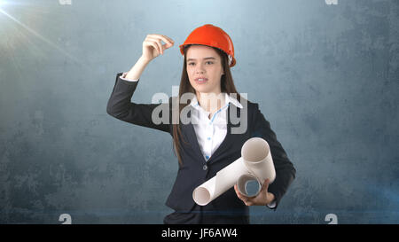 Building, developing, consrtuction and architecture concept -businesswoman in orange helmet with blueprint. Stock Photo