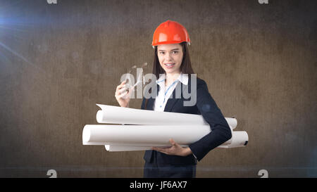 Building, developing, consrtuction and architecture concept -businesswoman in orange helmet, glasses with blueprint. Stock Photo