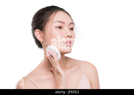Smiling girl holding powder cushion puff applying cosmetic powder on face Stock Photo