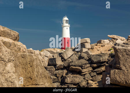 Portland Bill Lighthouse on a beautiful summers day, depicting the Quarries rock and boulder formation in the foreground with a clear blue sky.