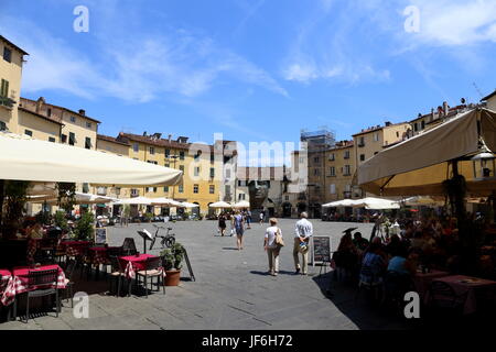 The Piazza dell´ Anfiteatro in Lucca city centre with tourists, restaurants and artwork by Igor Mitoraj. Stock Photo