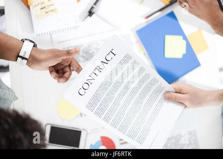 Overhead view of businessmen holding contract above table with papers Stock Photo