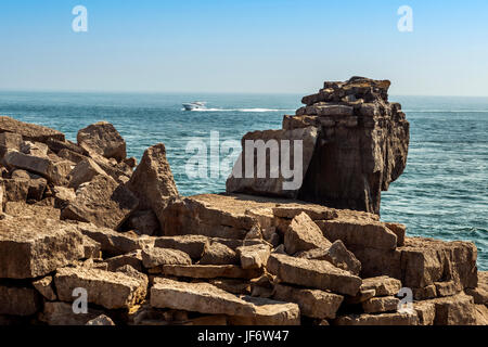 Seascape depicting the Pulpit Rock from the Quarries pathway, a passing cruiser surrounded by blue skies and calm seas on a beautiful summers day. Stock Photo