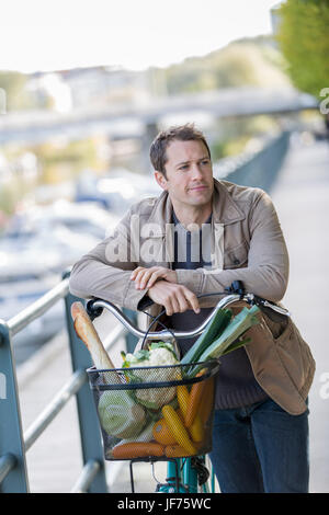 Portrait of man holding bicycle with vegetables in basket Stock Photo