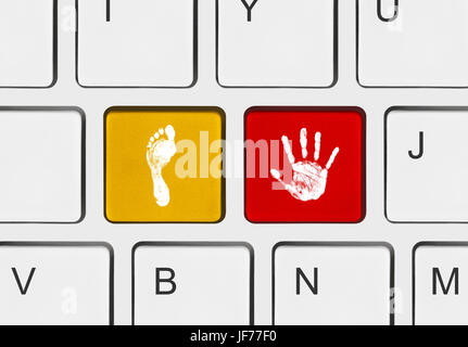 Printout of hand and foot on computer keys Stock Photo