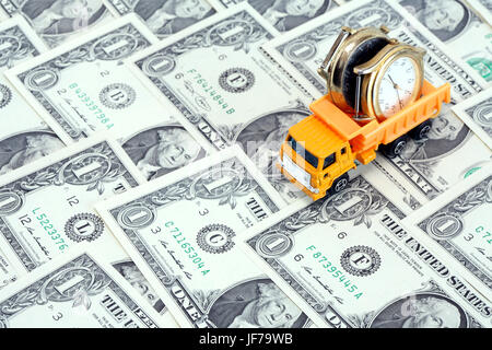 Business concept. Toy dump truck with wristwatch on dollar currency background Stock Photo