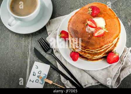 Celebrating Father's Day. Breakfast. The idea for hearty and delicious holiday breakfast: pancakes with butter, maple syrup and fresh strawberries, wi Stock Photo