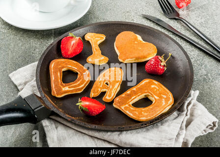 Celebrating Father's Day. Breakfast. The idea for a hearty and delicious breakfast: pancakes in form of congratulations - I love dad. In a frying pan, Stock Photo