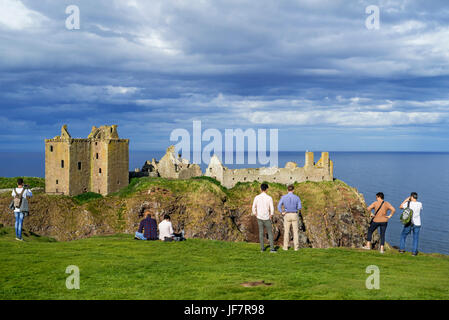 Tourists looking at Dunnottar Castle, ruined medieval fortress near Stonehaven on cliff along the North Sea coast, Aberdeenshire, Scotland, UK
