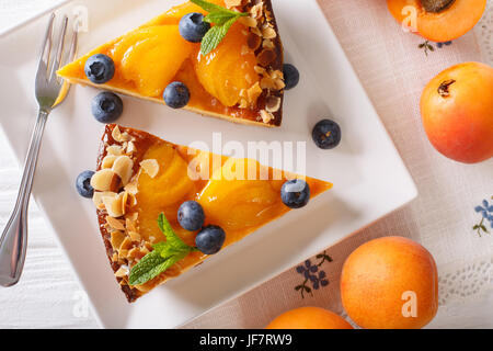 Apricot cake with blueberries, mint and nuts close-up on a plate. horizontal view from above