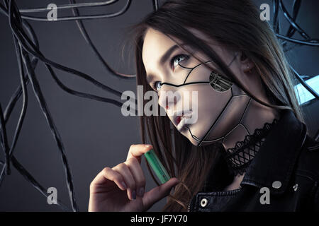 charming robot girl with cyberpunk style makeup holding battery in hand, concept energy saving Stock Photo