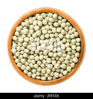 Dried green peas in wooden bowl. Small light green spherical seeds from the pods of Pisum sativum, used as vegetable or for sowing. Stock Photo