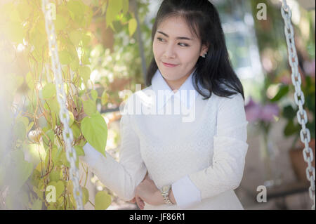 Young attractive Asian woman smiling in green garden. Stock Photo