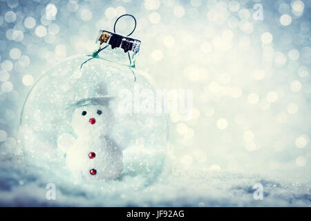 Christmas glass ball with snowman inside. Snowy, glitter background. Stock Photo